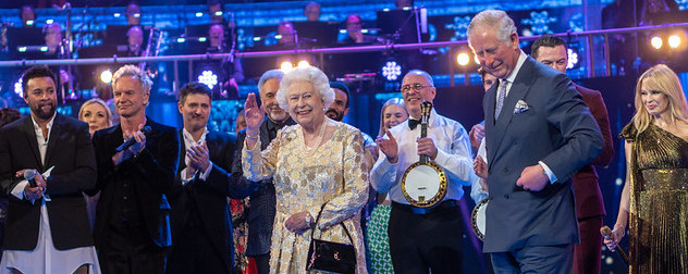 Queen Elizabeth II on stage with Prince Philip and various musicians and entertainers at Royal Albert Hall.