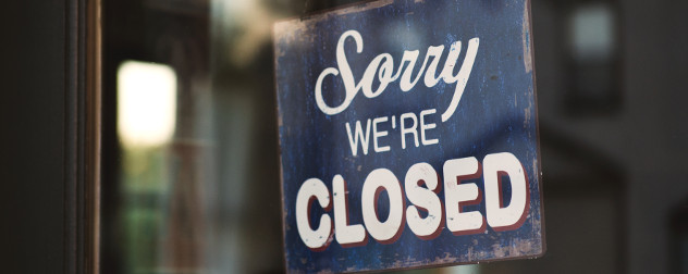 wooden sign that says 'Sorry, We're Closed' in a business window.