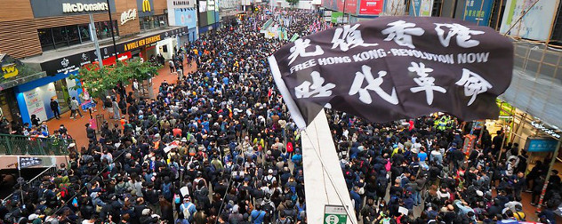 Hong Kong protest flag in foreground, with protesters in background.