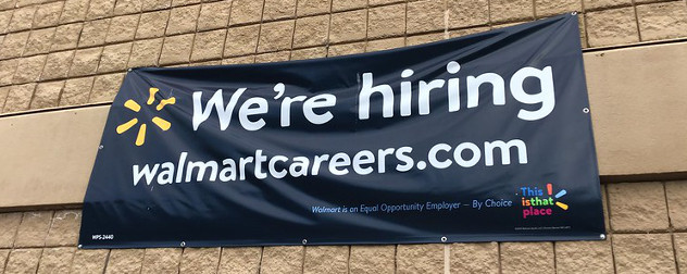 'We're Hiring' sign on the exterior of a Walmart store.