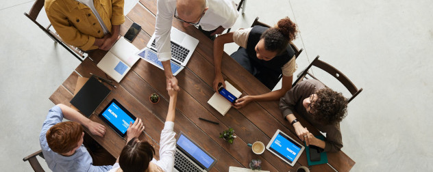 overhead view of businesspeople using mobile devices, and two shaking hands.