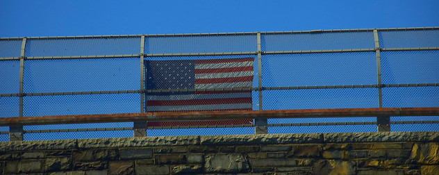 American flag hung on overpass fence.