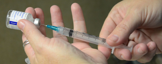 close view of medical provider drawing flu vaccine into a syringe.
