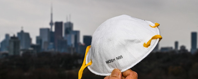 N95 mask held up with the Toronto skyline in the background.