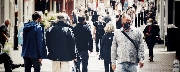 people walking on the street, some masked, in London.