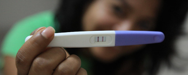 person out of focus, holding up a positive pregnancy test.