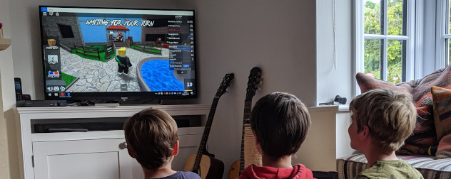 kids playing Roblox on a large screen.