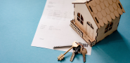 papers, a model wooden house, and a set of keys.