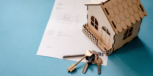 papers, a model wooden house, and a set of keys.