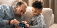 man with beard playing with a toy truck with a short-haired child.