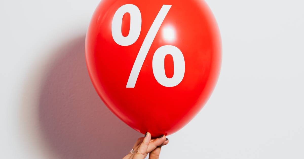 hand holding red balloon with the percent symbol.