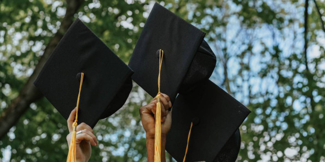 detail of graduation caps held in the air.