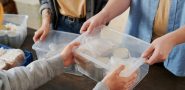 person hand over a box of food and canned goods (detail).