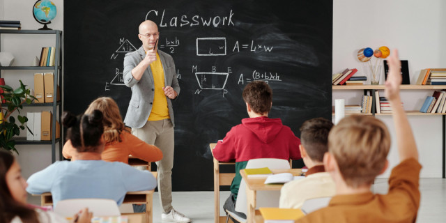 teacher calling on student with hand raised.