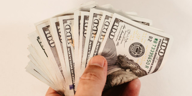 person holding 100 dollar bills.